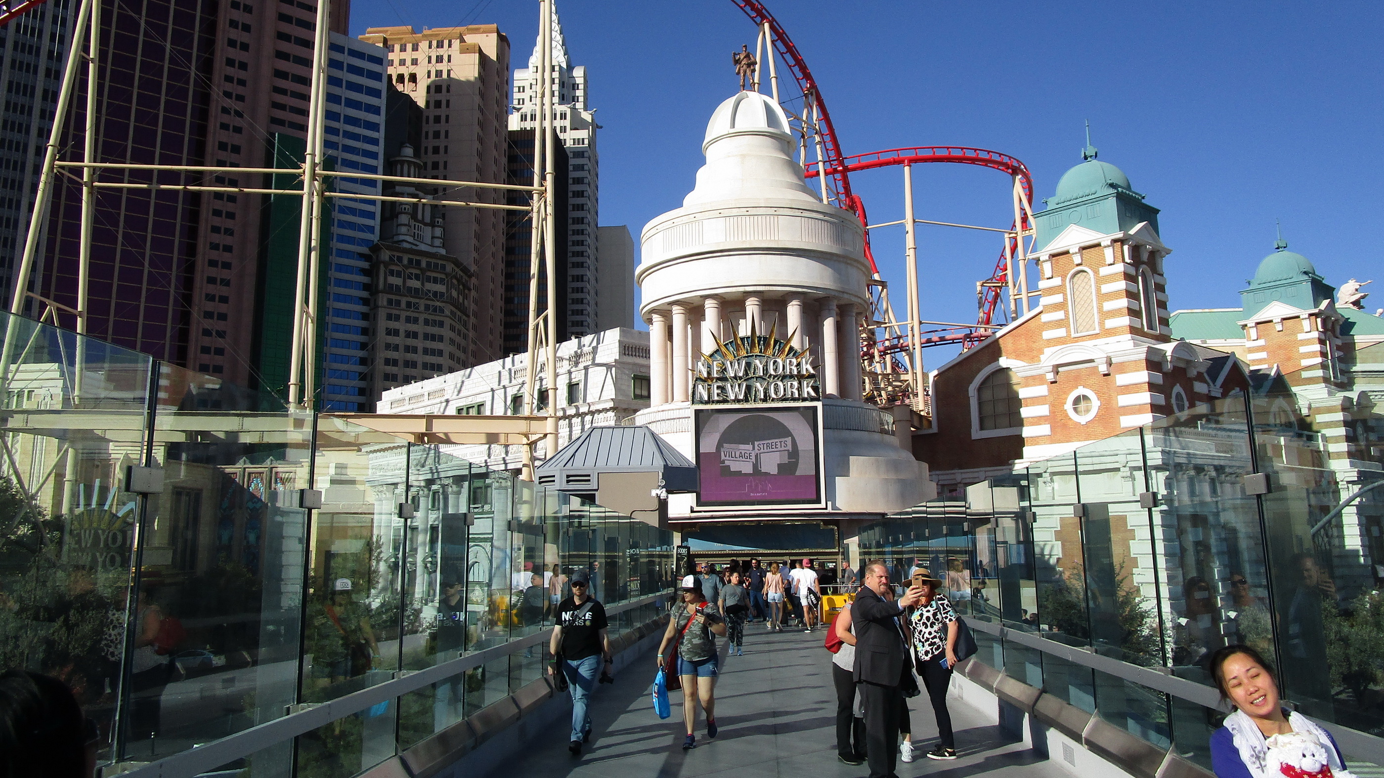 Pedestrians crossing a pedestrian bridge over the Las Vegas Strip in bright daylight