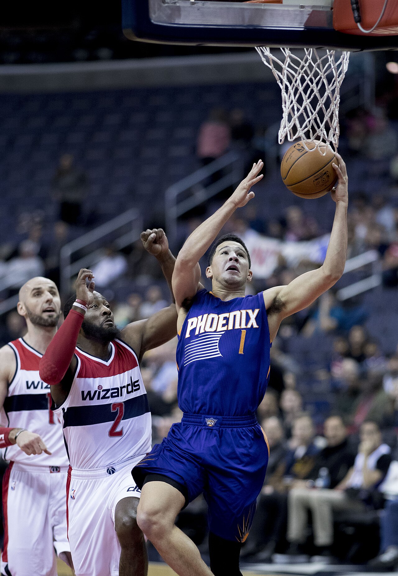 Devin Booker driving to the basket in a Phoenix Suns uniform.