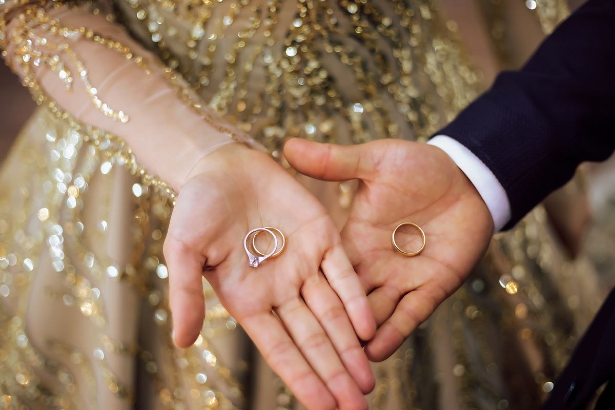 A bride and groom holding hands showing wedding bands