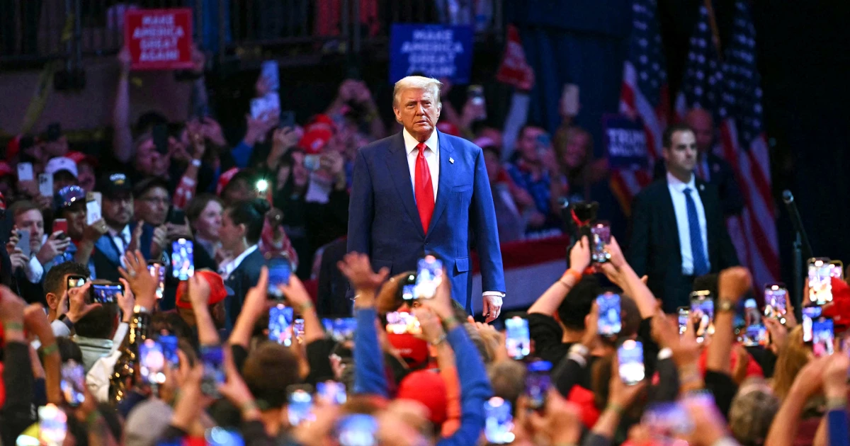 Donald Trump at a rally with supporters holding up phones