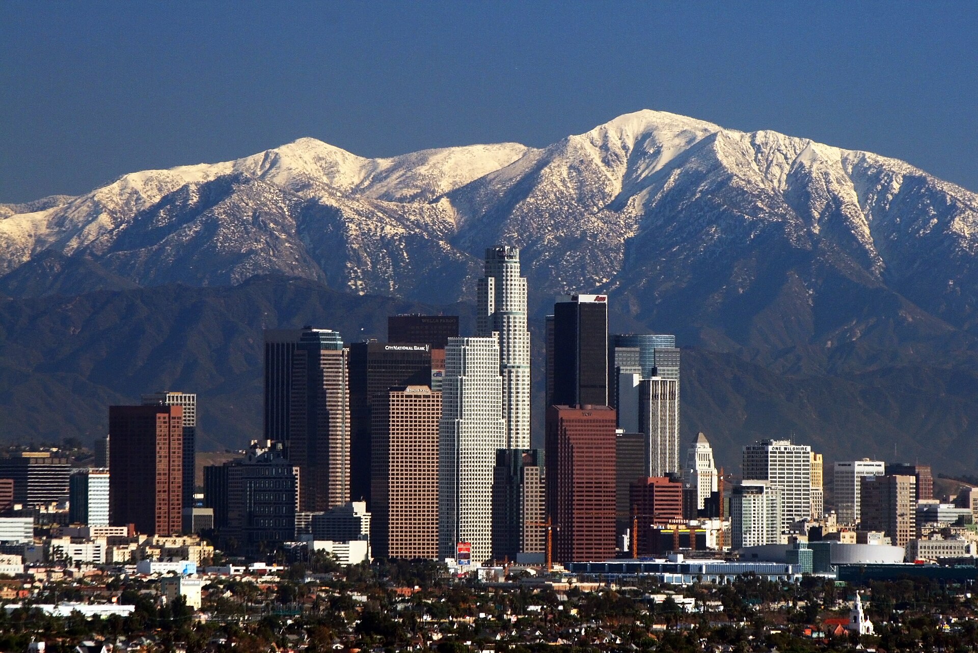 Downtown Los Angeles skyline in daylight with the San Gabriel Mountains behind it — the city President Trump suggested Iran could