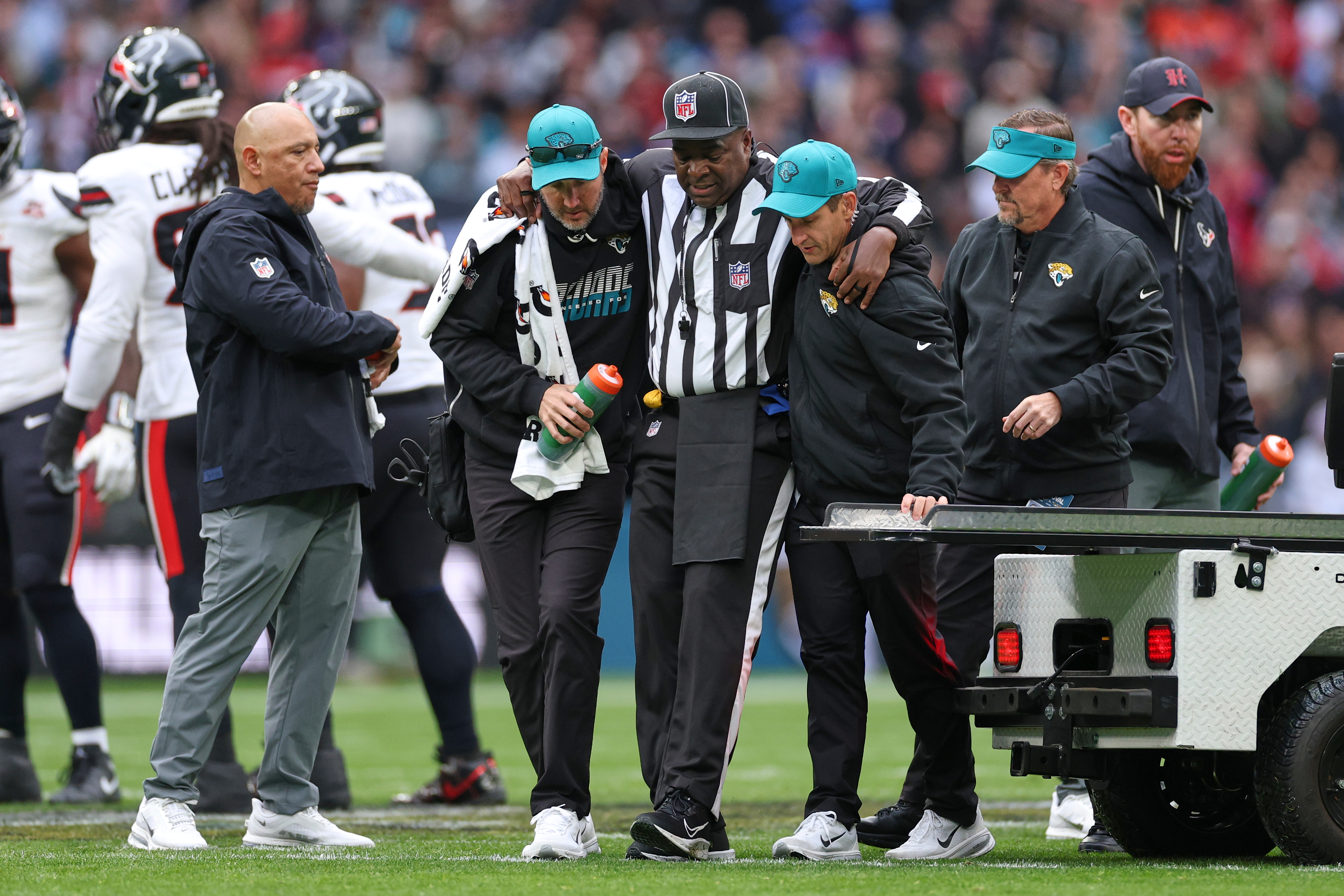 Umpire Larry Smith is assisted from the field after getting injured during the Texans-Jaguars game in London