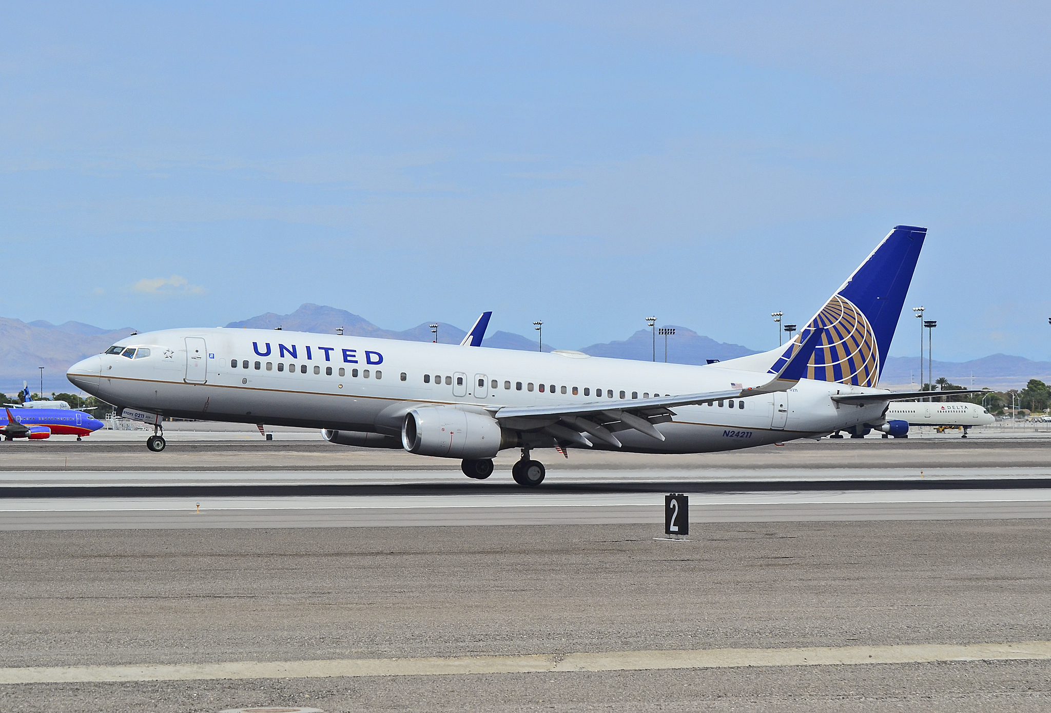 A United Airlines 737 on the runway at Harry Reid International Airport in Las Vegas, desert mountains behind the airfield