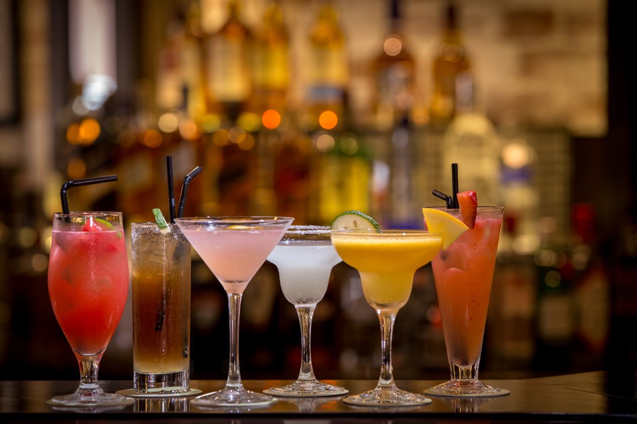 Colorful cocktails lined up on a bar counter