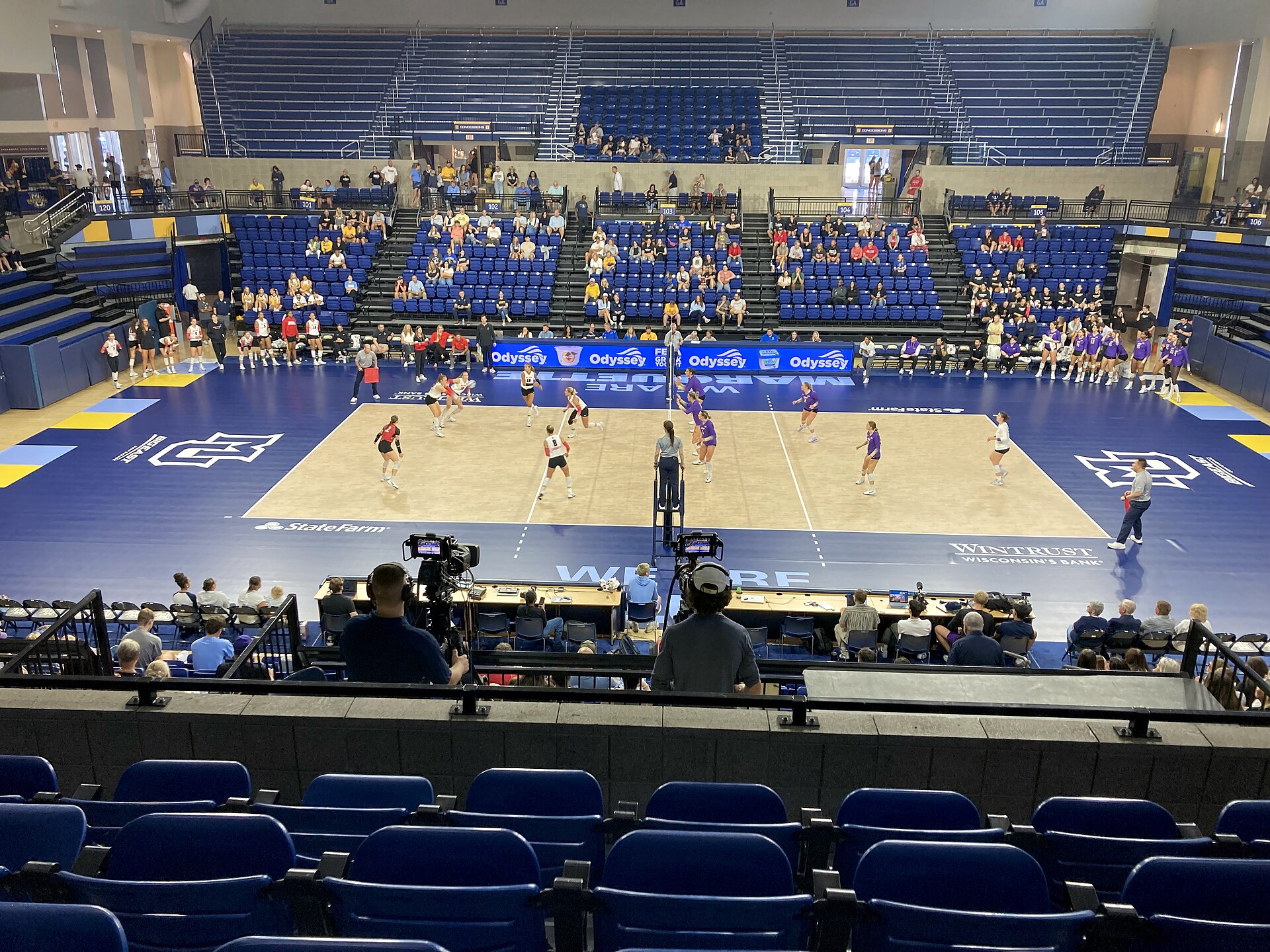 Women's volleyball match in progress in a bright indoor arena