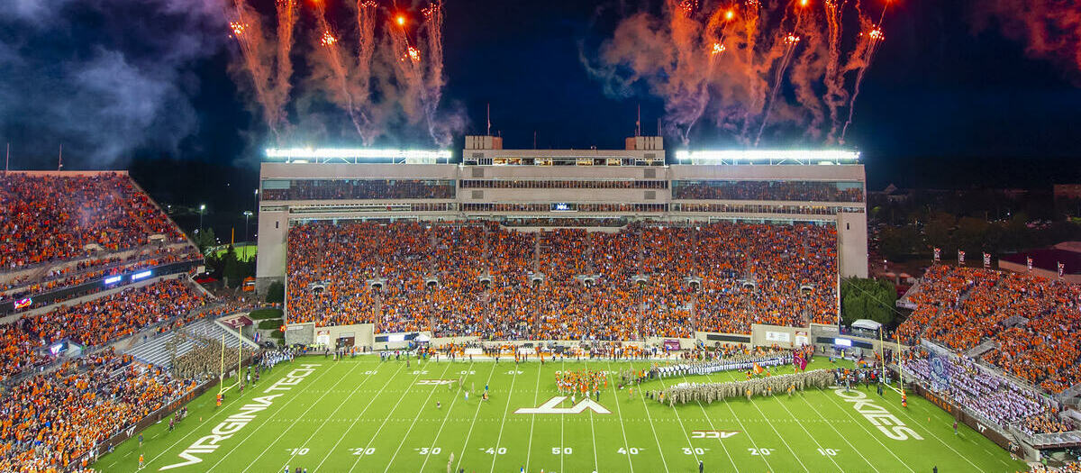 Lane Stadium packed under the lights at night, fireworks bursting over the stands