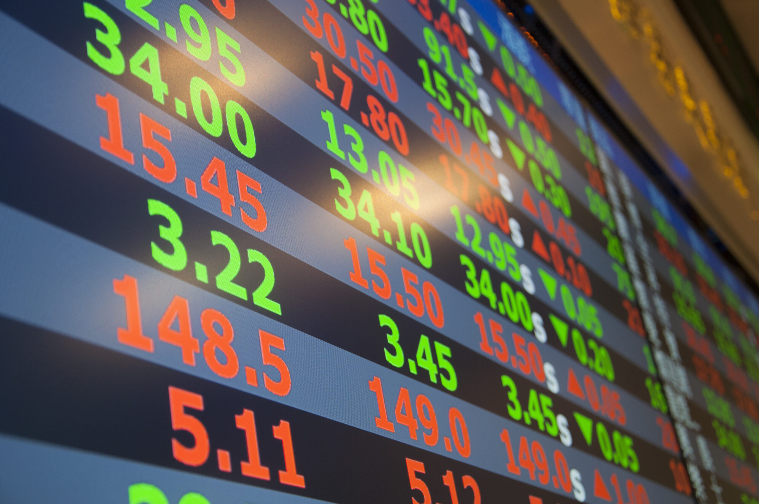 A stock market ticker board glowing with green numbers.