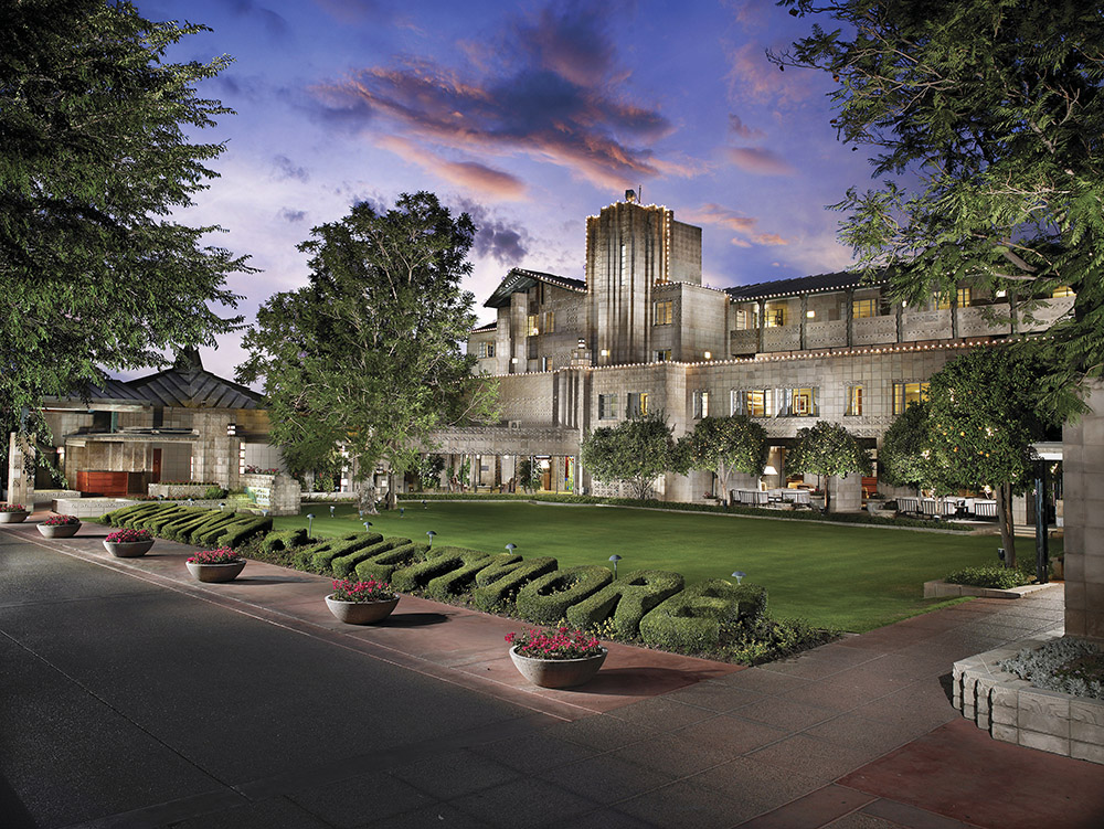 The Arizona Biltmore's main building at dusk, with the BILTMORE hedge in the foreground