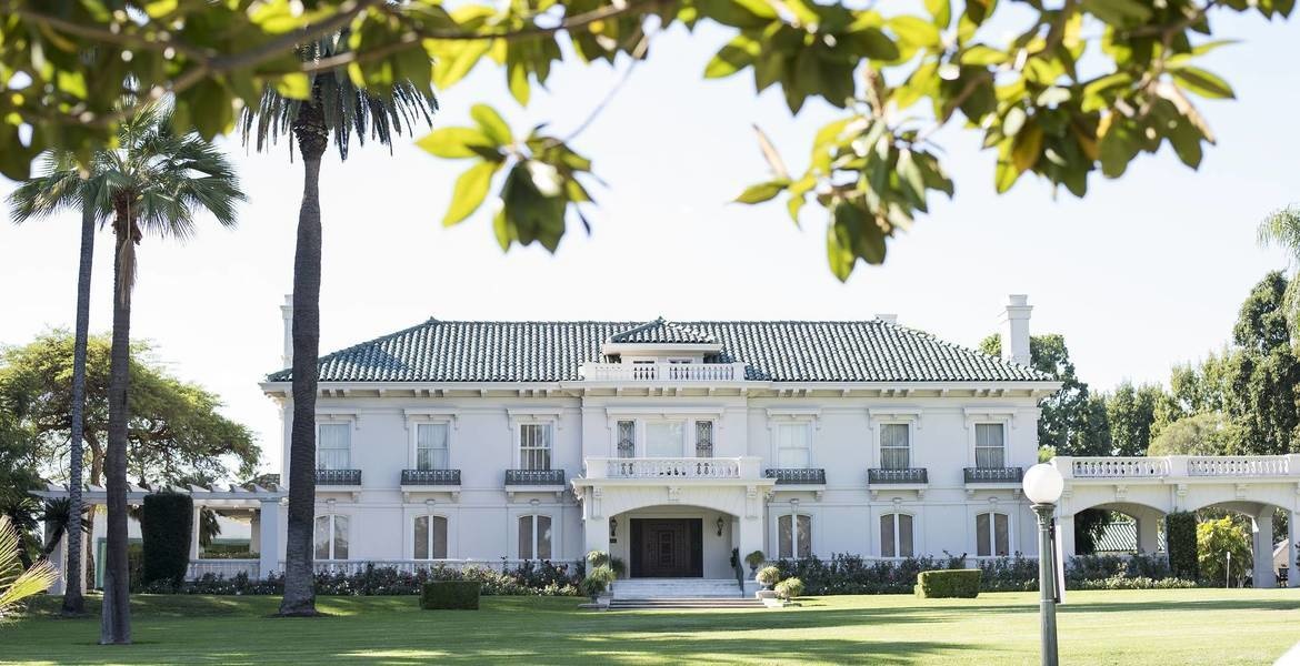 A closer view of Wrigley Mansion's white stucco architecture and landscaped grounds