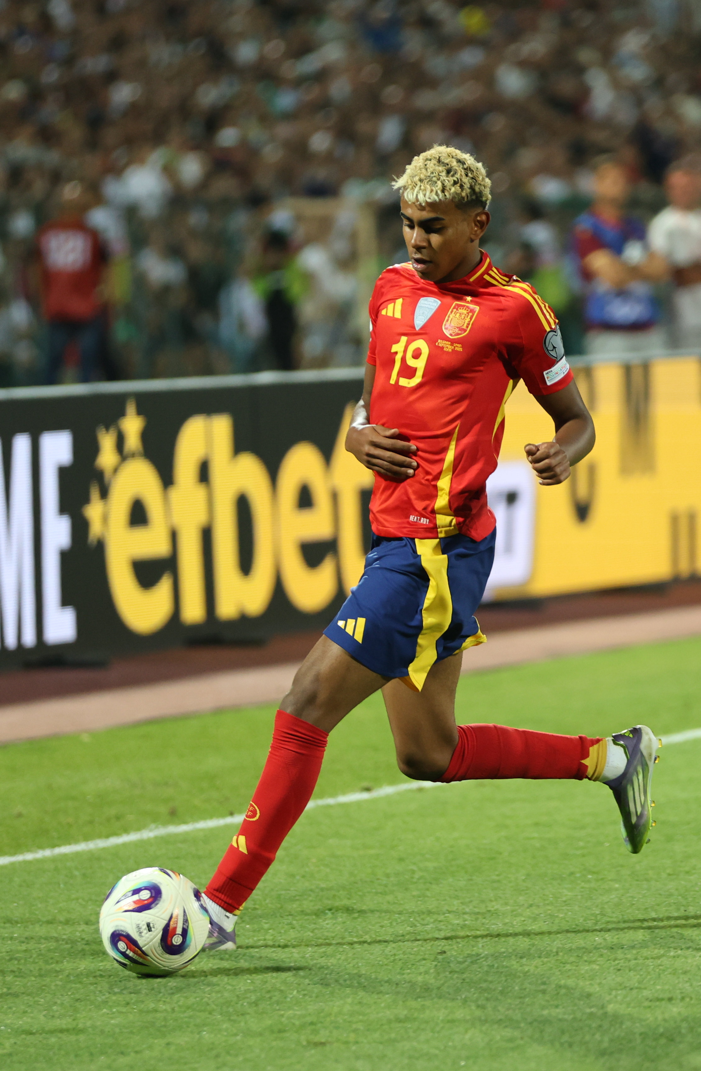 Lamine Yamal in Spain's red No. 19 kit, running with the ball at his feet