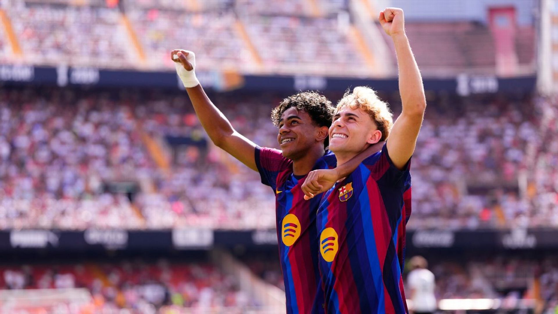 Lamine Yamal (left) and Fermín López celebrate in Barcelona's home kit, arms raised, in front of a stadium crowd