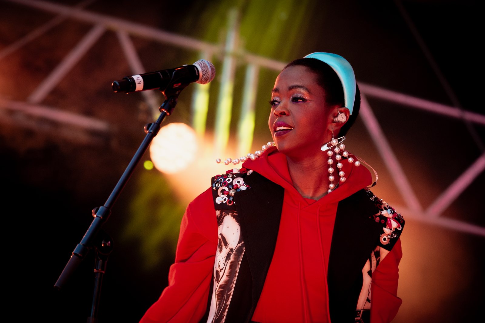 Lauryn Hill performing live at Kongsberg Jazzfestival in 2019, red hoodie and pearl earrings, at the microphone